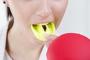 person putting a yellow mouthguard in their mouth