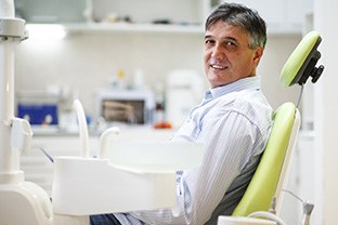 Older man sitting in dental chair smiling
