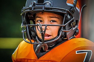 a child wearing a football helmet and athletic mouthguard