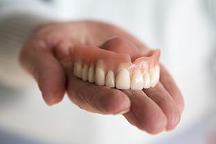 Hand holding an upper denture