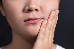 close up person holding their jaw in pain 