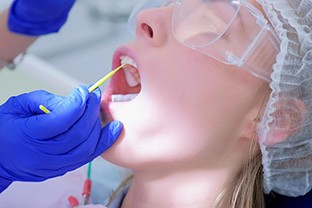A dentist applying fluoride varnish to a woman’s teeth