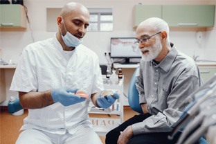 a dentist explaining about implant dentures in Peabody