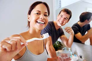 man and woman brushing their teeth