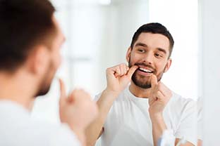 man flossing in front of a mirror
