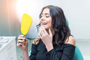 dental patient admiring her smile in a mirror