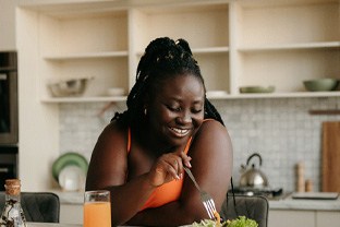 Woman smiling while eating healthy meal at home