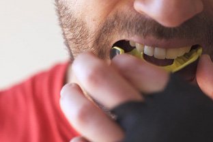 Man putting on yellow and black mouthguard