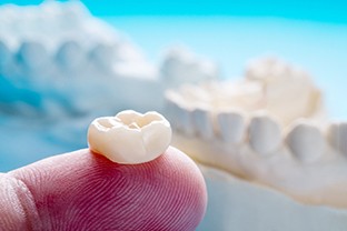 a person holding a dental crown in Peabody