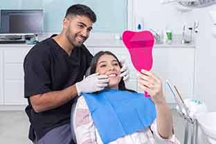A woman admiring her smile with a hand mirror