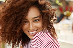 Closeup of woman with curly hair smiling in red and white shirt