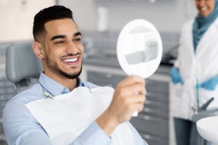 Man with straight teeth smiling at reflection in mirror