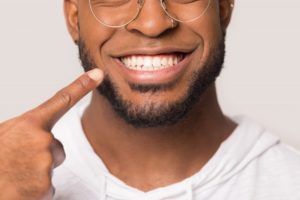 close-up of a man pointing to his smile with dental implants in Peabody