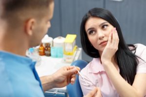 woman with toothache talking to dentist about root canal cost