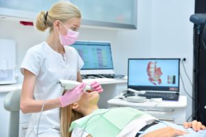 Dentist in white scrubs digitally viewing a patient's teeth